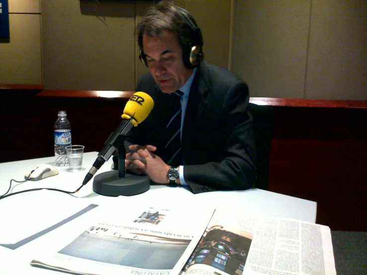 a man sitting at a table with headphones on while talking into a microphone