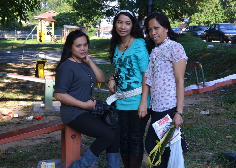 three young women pose together near the playground