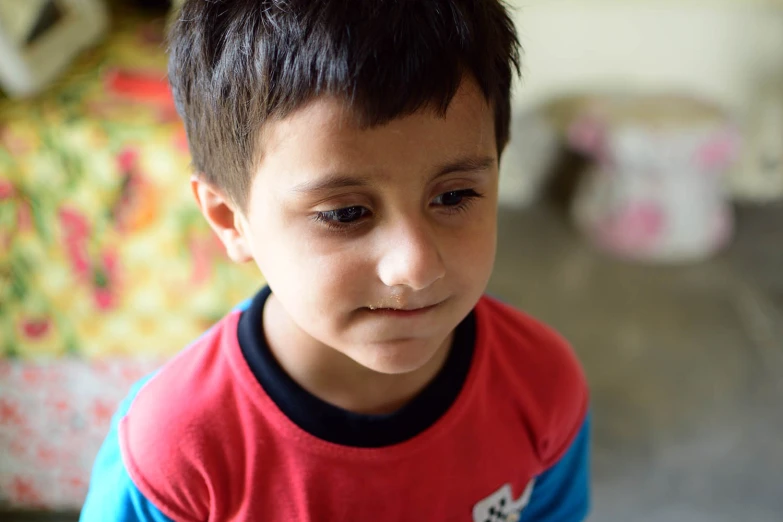a boy in a red and blue shirt stares to the left