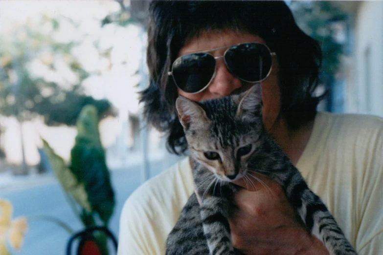 a man in glasses holding a cat with its face obscured by it