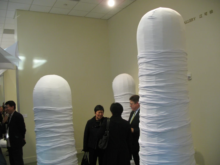 three women stand next to giant stack of paper with a boy standing in the background