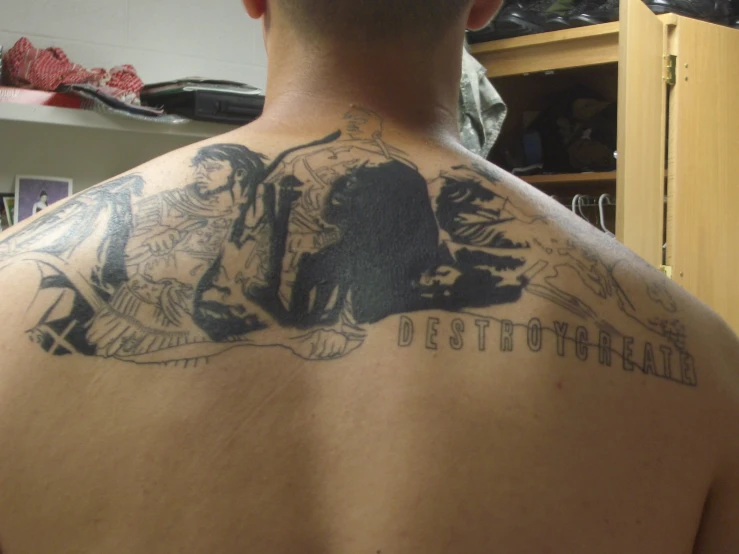 man with tattoos on back and arm looking at mirror