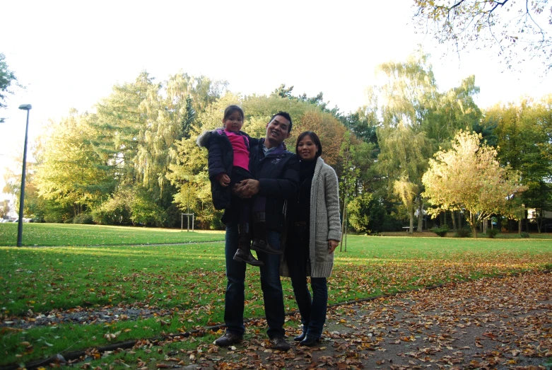 a couple holding children on their shoulders standing in the park