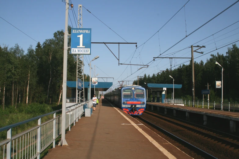 a blue train pulling into a station with no passengers