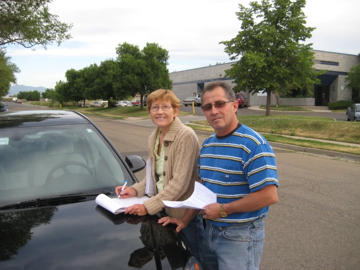 a woman standing next to a man holding a piece of paper