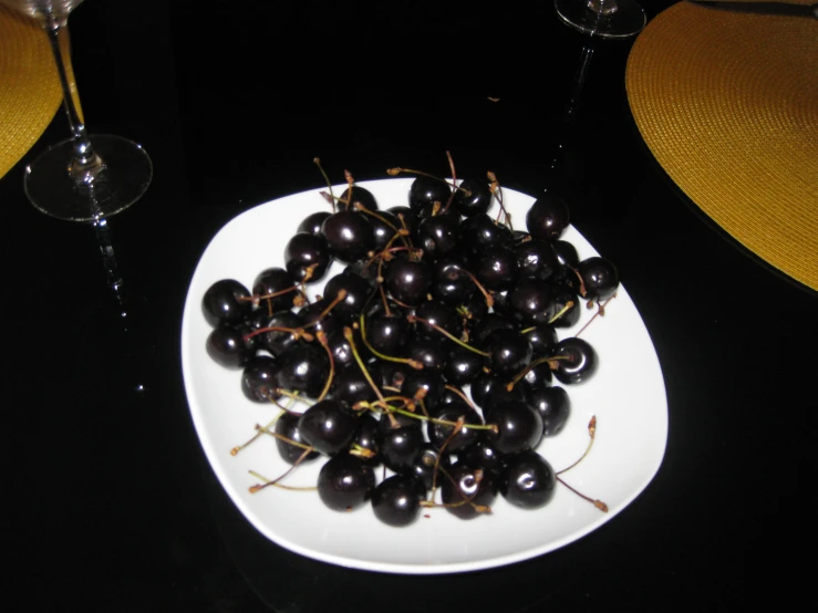 blackberries sit on a white plate on a dining table