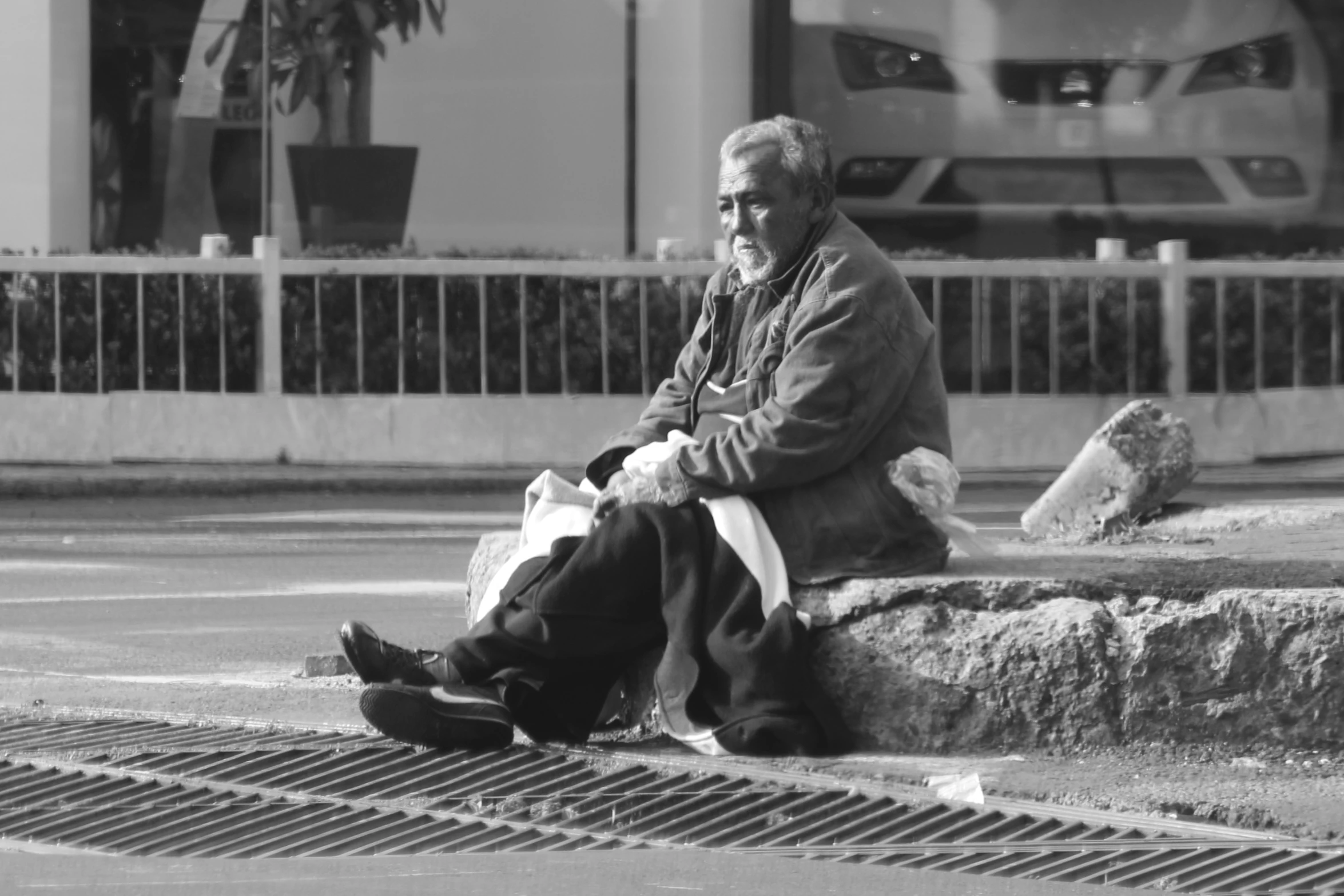 a person sitting on a street with his foot up