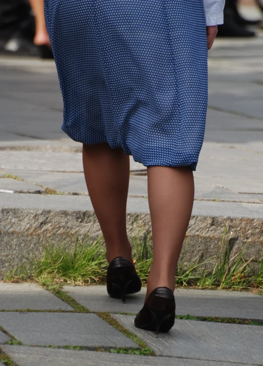 a woman in blue dress walking down the sidewalk