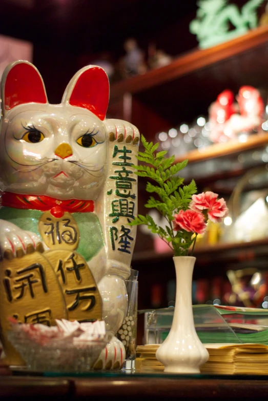 the cat figurine is sitting next to a vase of flowers