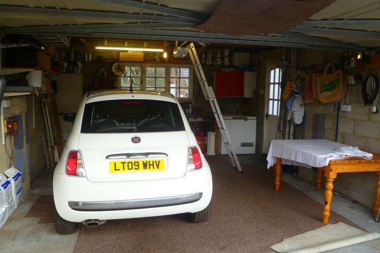 a car parked inside of a garage filled with boxes and items