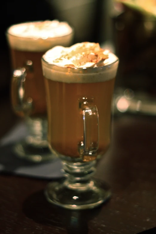 two glasses with beverages are sitting on a table