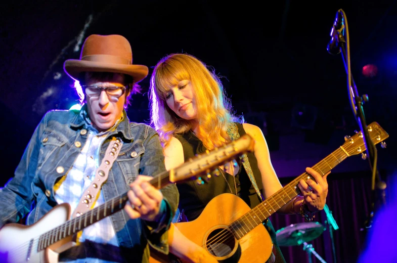 the woman is playing the guitar and the man is playing the guitar