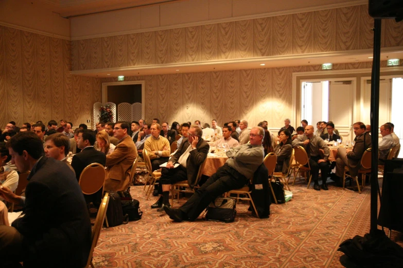 many people are sitting in the middle of a room with gold walls