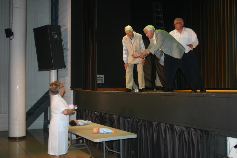 people stand on a stage with table and chairs