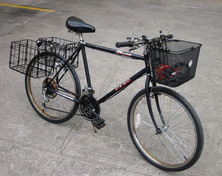 a black bicycle with a basket sitting on the concrete