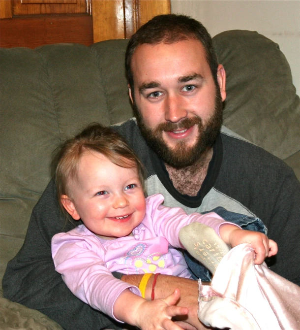 a bearded man and his baby on the couch