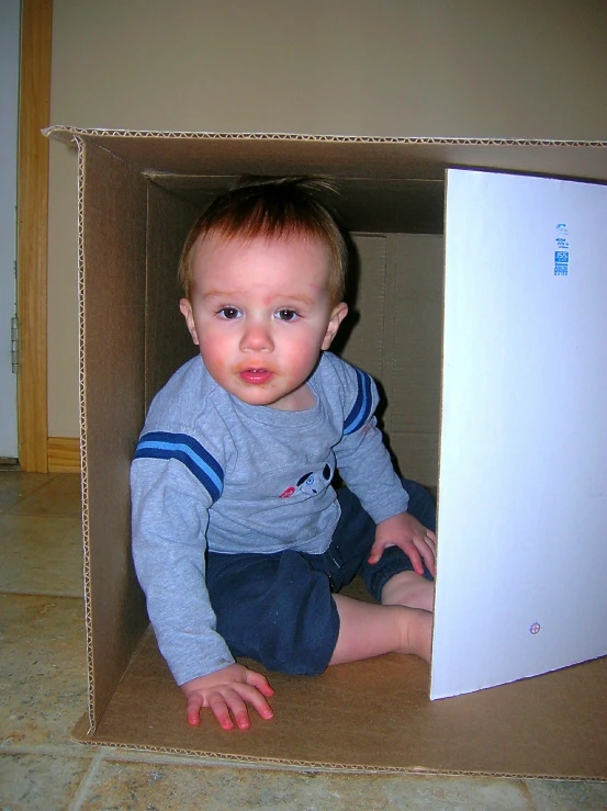 small child sitting in a cardboard box with a big surprise