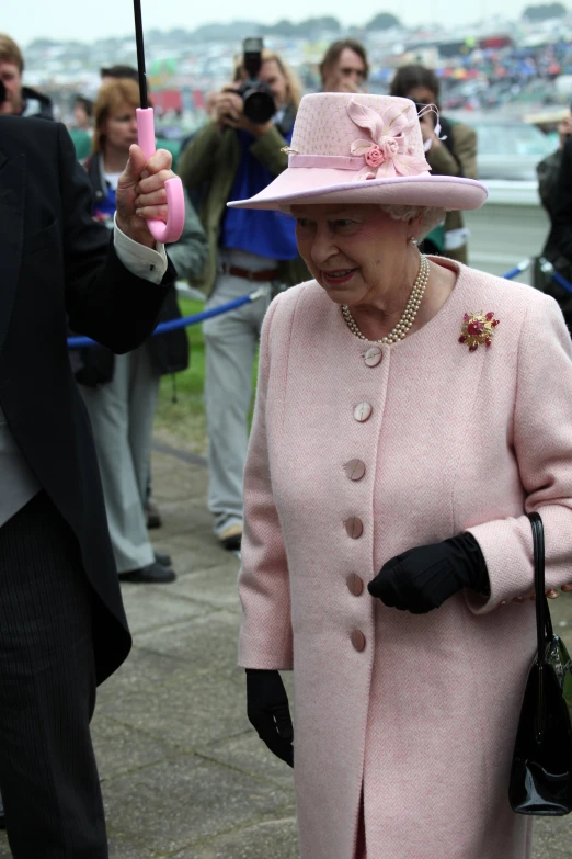 an old woman dressed in pink and black holds up a pink umbrella