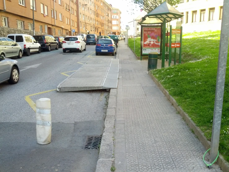a sidewalk near a bus stop next to a small street