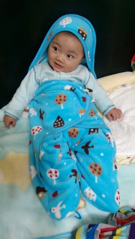 baby in a blue blanket and pacifier laying down on a bed