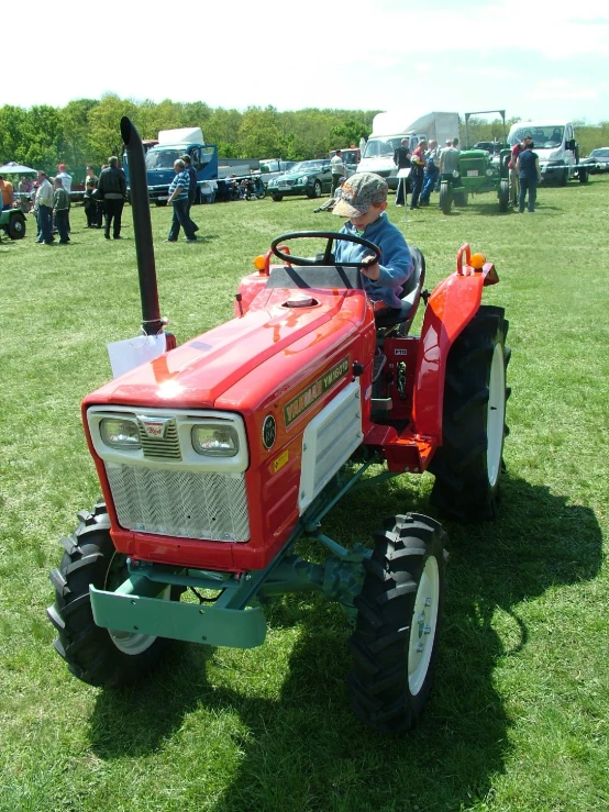 a small boy riding on the back of a tractor in a field