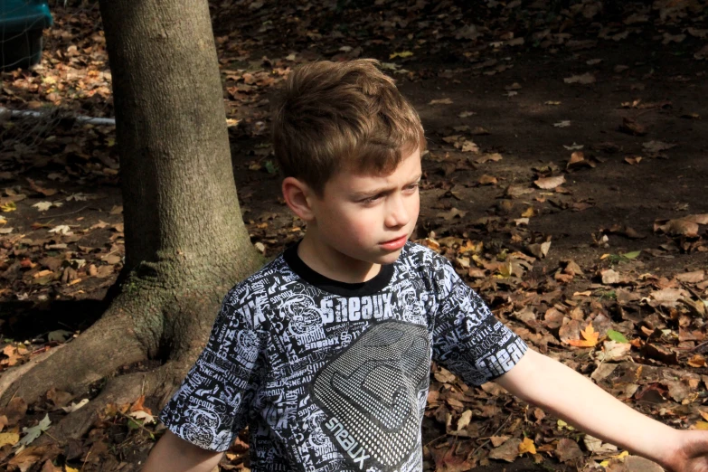 a boy with brown hair standing in the leaves