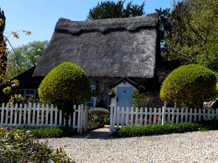 an old thatched cottage with a white picket fence