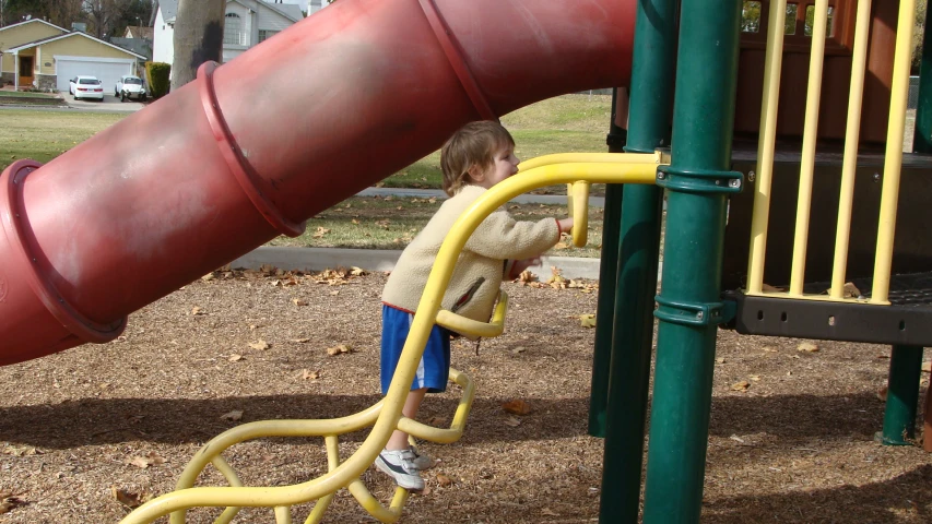 a  climbing on the yellow and red plastic slide