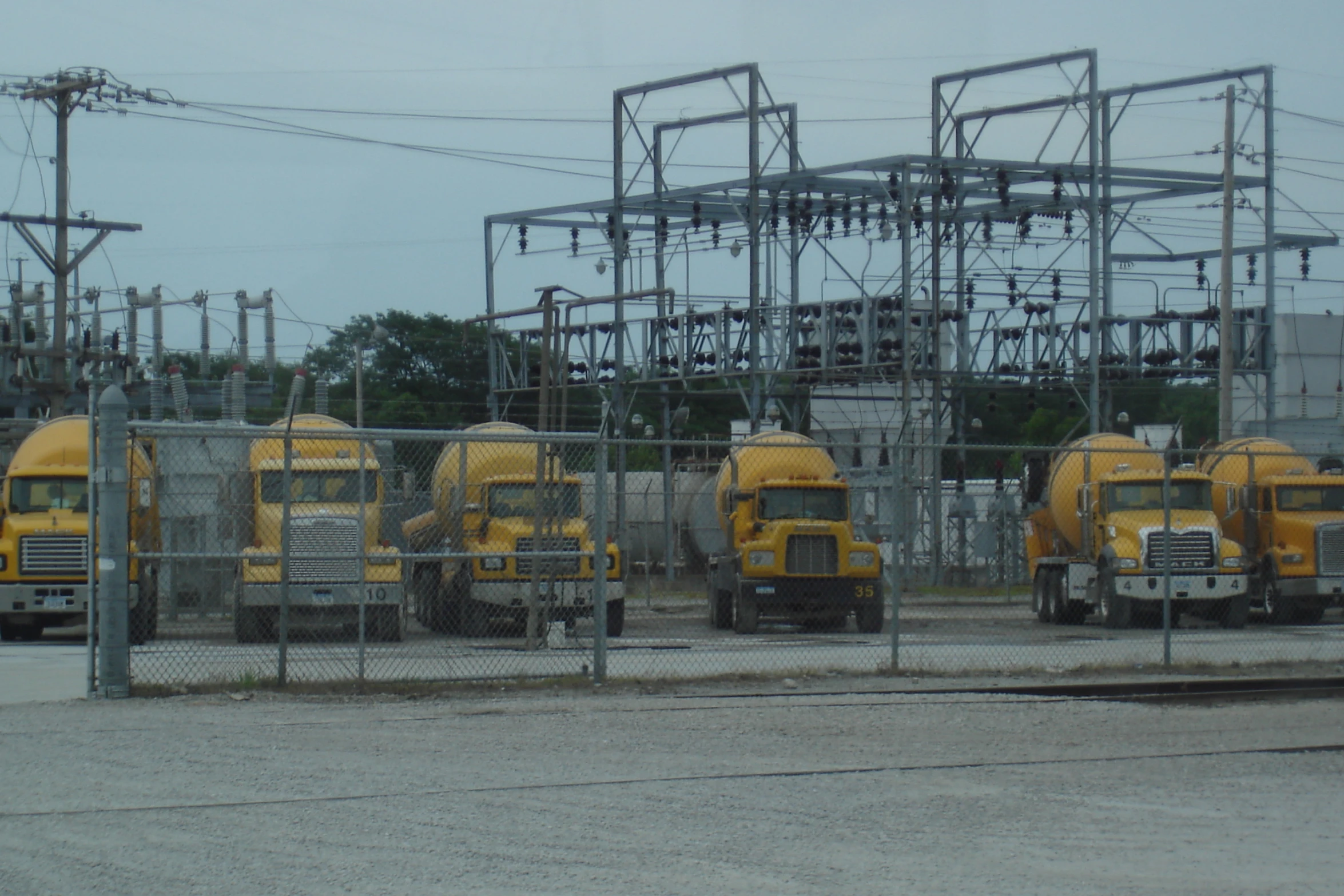 a large group of yellow trucks parked at an industrial plant