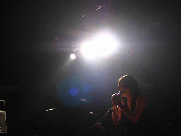 woman standing at microphone in dark spot during concert