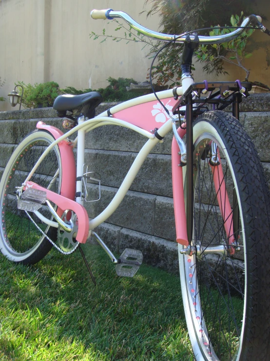 the pink and white bicycle is parked next to the building