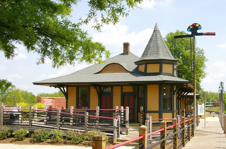 a small yellow and black train depot next to trees