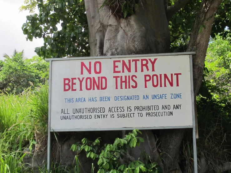a sign is posted beside a tree