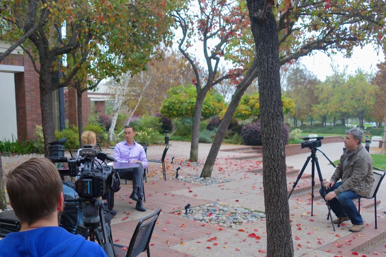 three people in a park with film equipment set up