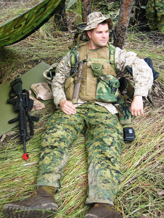 the man wearing camouflage clothing sits next to a machine