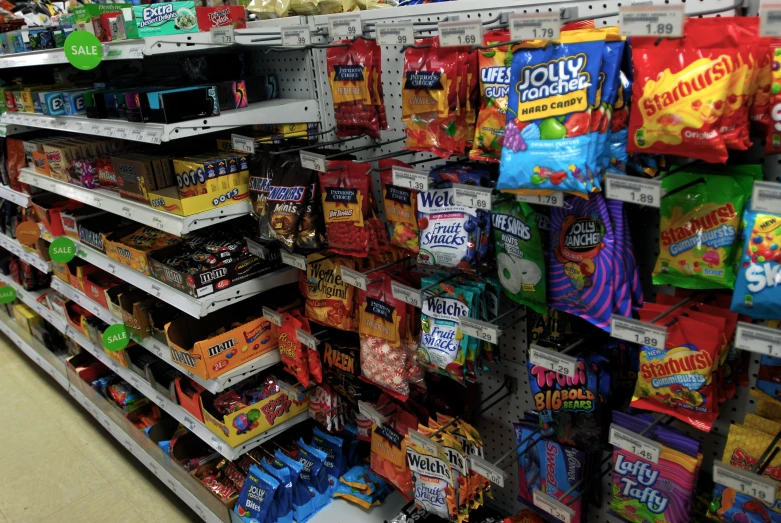 the shelf in a grocery store has candy and chips