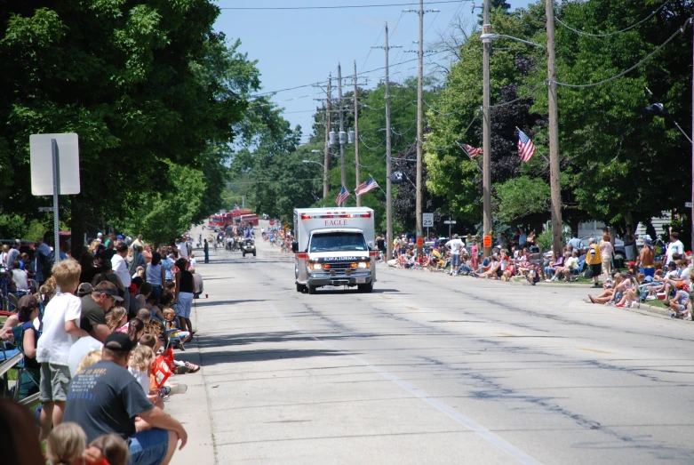 an ambulance drives through a parade with lots of spectators