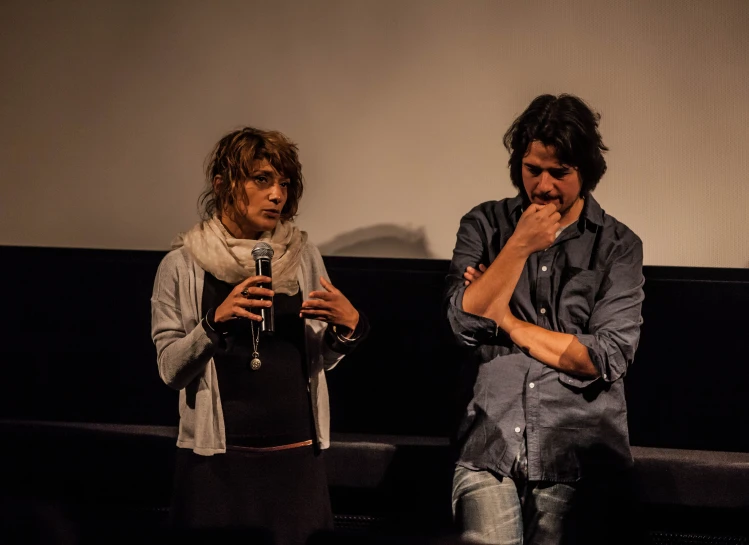 two people are sitting on a bench and one of them is holding his hands to their mouths