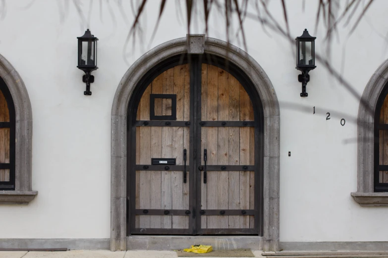 a white building with two brown doors and three black frames