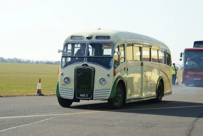 a bus and a truck on a roadway with a field behind it