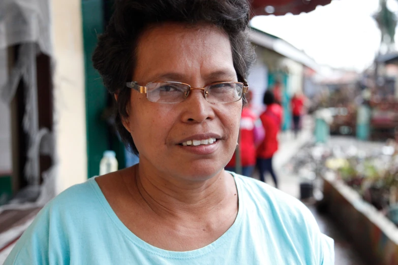 a woman with glasses standing by a street