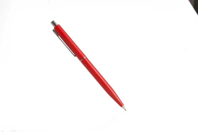 a red pen resting on a white surface