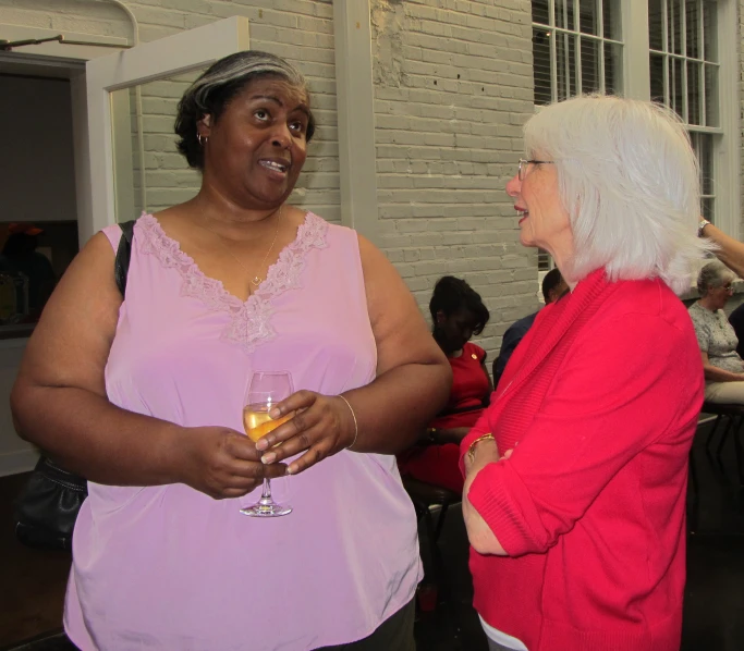 two ladies laughing while one holds a glass