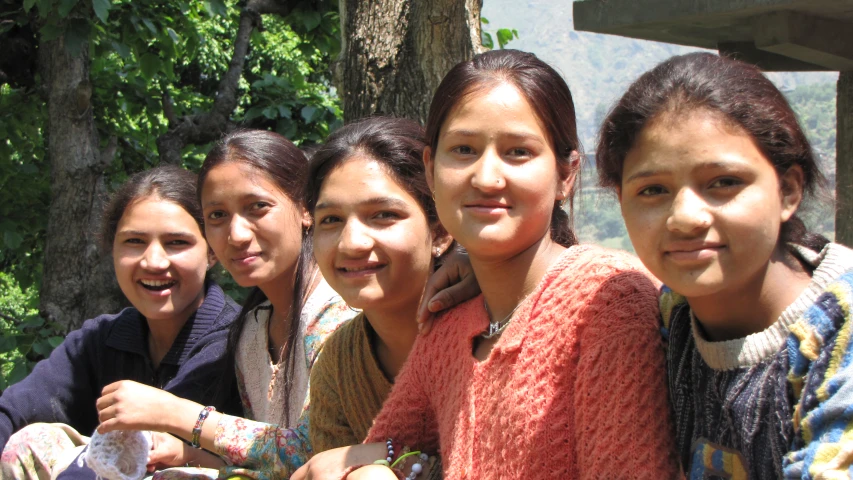 four girls, each holding a basket of fruit and one of them has a cell phone