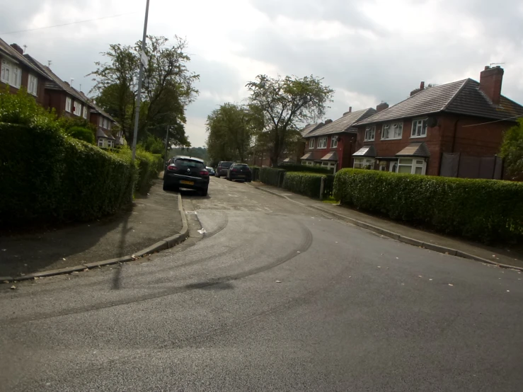 cars driving down the street in a residential neighborhood