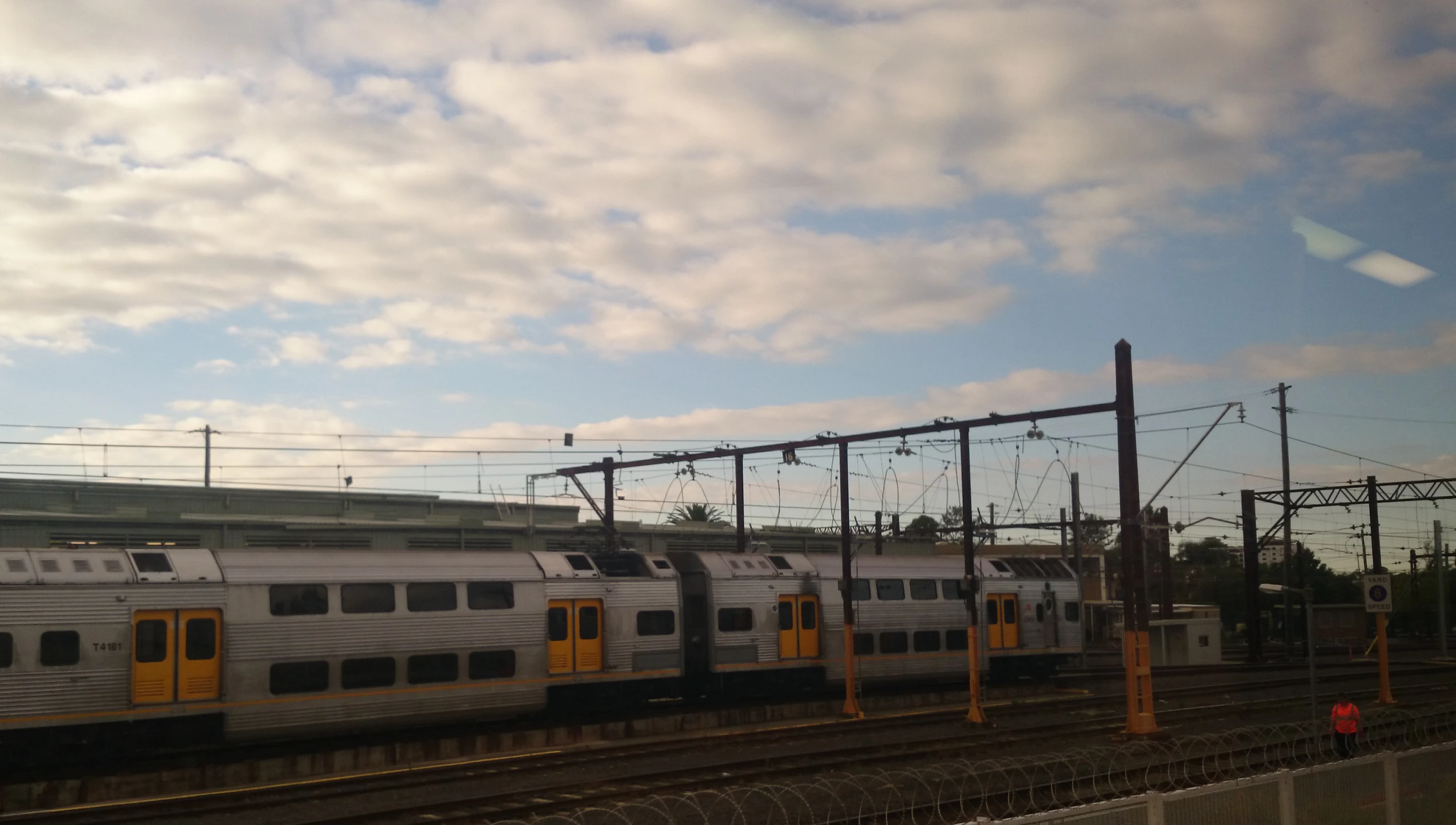 three passenger trains with yellow doors stand on the tracks