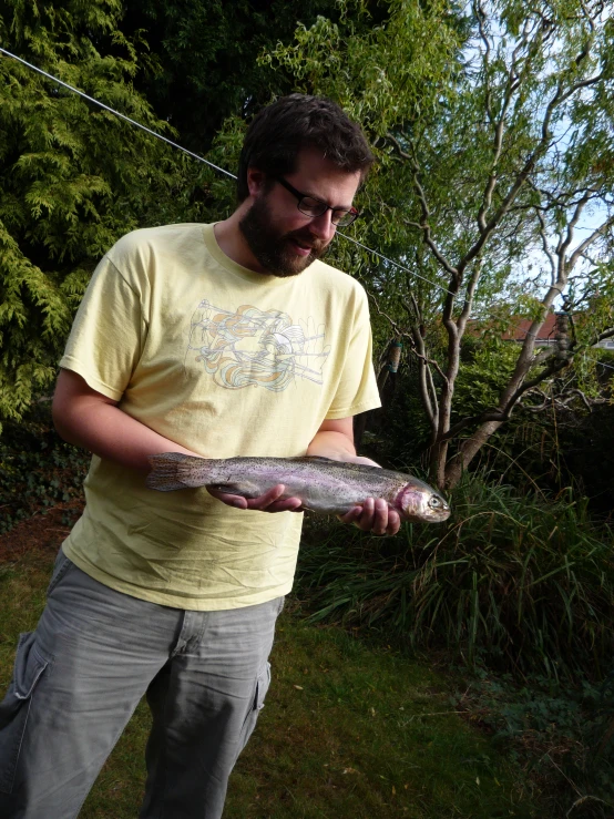 a man with glasses holding a large fish