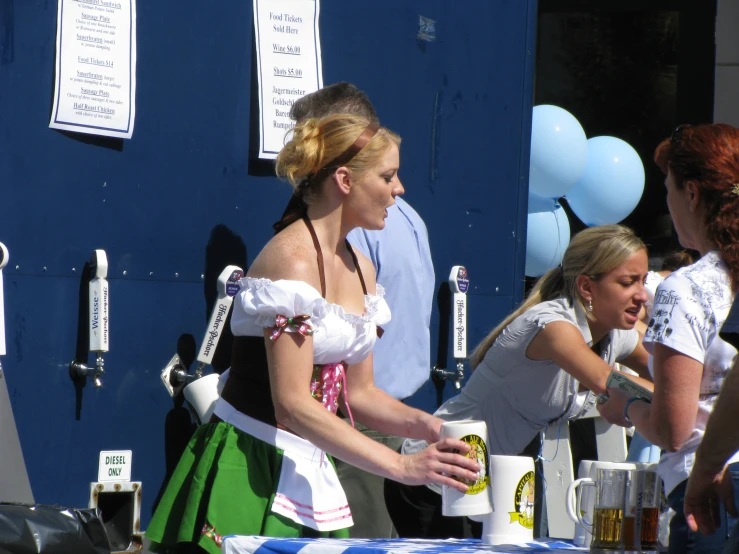 woman in costume serving drinks to others on the sidewalk