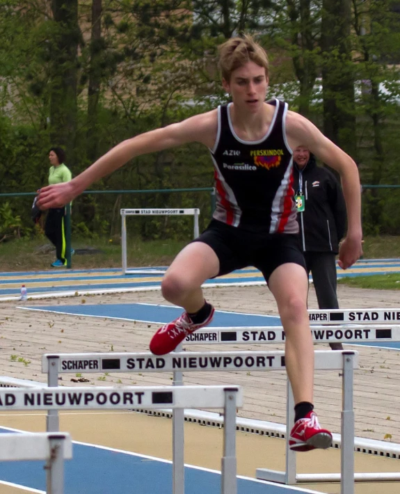 a male runner in black and red running a track