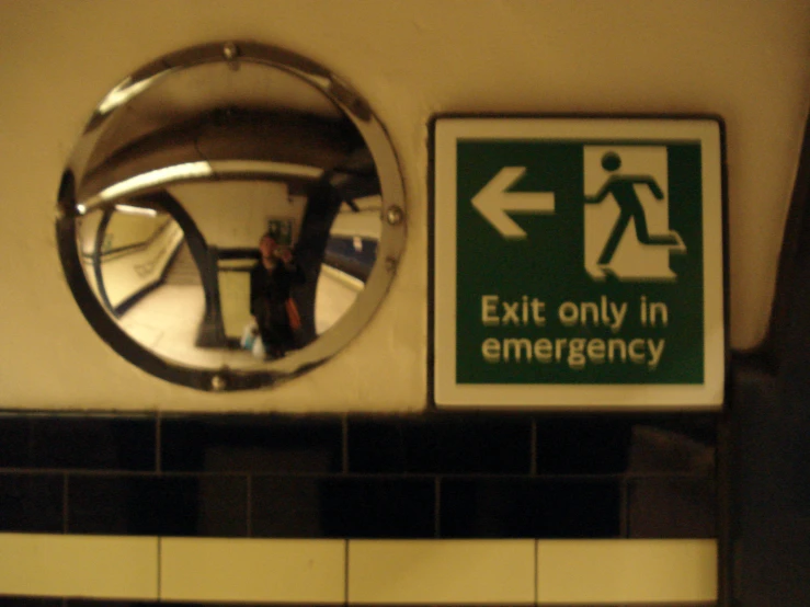 exit only in emergency with mirror and reflection in wall